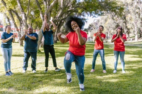 A woman with curly hair dancing in a garden